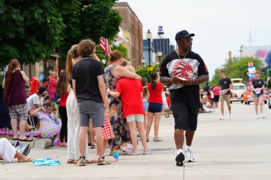 Sheboygan, Wisconsin ABD - 4 Temmuz 2024: Çocuklu aileler 4 Temmuz bayramı boyunca kaldırımlarda oturdu ve Özgürlük Festivali yürüyüşünü izledi.