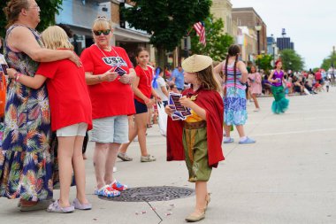 Sheboygan, Wisconsin ABD - 4 Temmuz 2024: Çocuklu aileler 4 Temmuz bayramı boyunca kaldırımlarda oturdu ve Özgürlük Festivali yürüyüşünü izledi.
