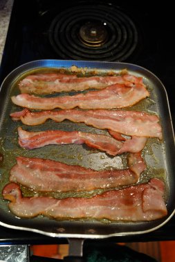 Domuz pastırması, kahvaltıda kızartma tavasında pişiyor..