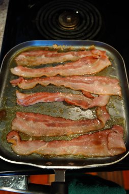 Domuz pastırması, kahvaltıda kızartma tavasında pişiyor..