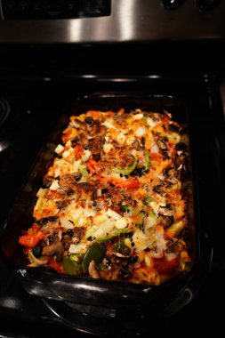 Karışık sebzeli makarna güveci sobanın üzerinde iki cam tavada oturur..