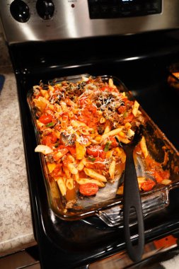 Karışık sebzeli makarna güveci sobanın üzerinde iki cam tavada oturur..