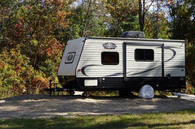 Yeni Lizbon, Wisconsin ABD - 10 Ekim 2024: 2016 Viking Ultra-Lite 17RD seyahat kampçısı bir ormanda oturuyor.