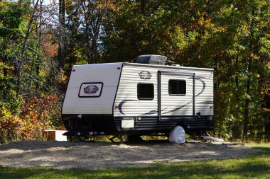 Yeni Lizbon, Wisconsin ABD - 10 Ekim 2024: 2016 Viking Ultra-Lite 17RD seyahat kampçısı bir ormanda oturuyor.
