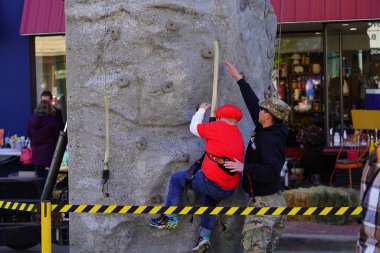 Beaver Dam, Wisconsin USA - October 27th, 2024: Young kids challenge themselves on a rock climbing wall outside at a Fall Festival. clipart