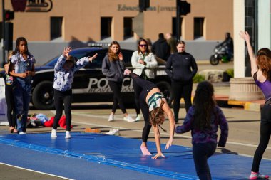 Beaver Dam, Wisconsin USA - October 28th, 2024: Young Gymnastic girls doing flips and cartwheel moves in the middle of the street during a fall festival event. clipart