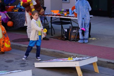 Beaver Dam, Wisconsin USA - October 26th, 2024: Young children and toddlers at a community Fall Festival Halloween event played Cornhole bean bag game to get candy reward during Trick or Treating. clipart