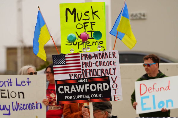 Madison, Wisconsin USA - March 29th, 2025: Liberal Democrats protest with signs in a large group in front of Tesla Dealership showroom during the national Tesla Takedown event.