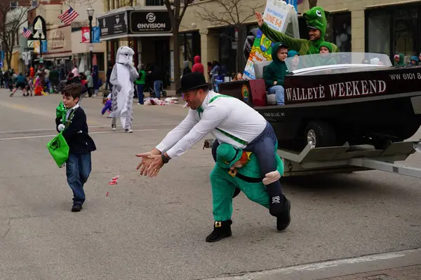 Fond du Lac, Wisconsin ABD - 15 Mart 2025: Cemaat üyeleri ve Yerel Örgütler 2025 St. Patrick Günü Yürüyüşüne katıldı ve çocuklara şeker dağıtarak sokaklarda dolaştı.
