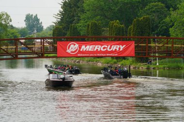 Fond du Lac, Wisconsin USA - 7 Haziran 2025: Mercury tekneleri ile nehirde ve halk parkında gezen insanlar.