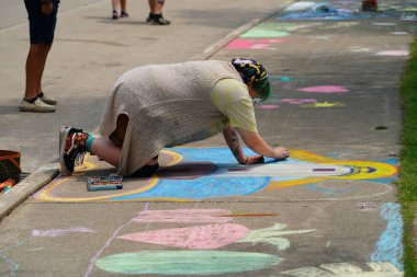 Fond du Lac, Wisconsin USA - 7 Haziran 2025: Genç kızlar kaldırımları halk parkındaki resimlerle renklendirmek için renkli tebeşir kullanıyorlar.