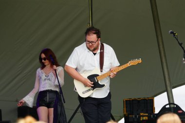 Kız konserde sahnede gitar çalıyor.