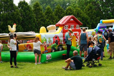 Fond du Lac, Wisconsin USA - 7 Haziran 2025: Aile üyeleri ve çocuklar engelli parkurda şişme şişme evlerde eğlendiler.