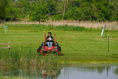 New Lisbon, Wisconsin USA - May 23rd, 2025: Man using riding lawn mower to cut their grass on their property yard.