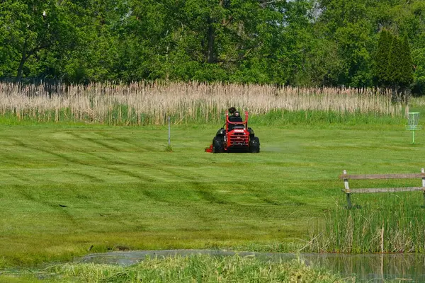 Yeni Lizbon, Wisconsin ABD - 23 Mayıs 2025: Çim biçme makinesiyle bahçelerinde çimleri biçen adam.