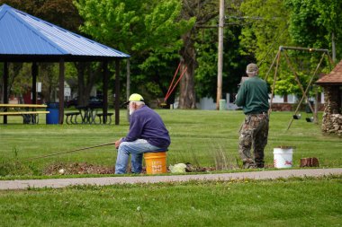 Tomah, Wisconsin ABD - 28 Mayıs 2025: İki yaşlı adam birlikte bir gölde balık tutuyorlar.