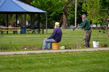 Tomah, Wisconsin ABD - 28 Mayıs 2025: İki yaşlı adam birlikte bir gölde balık tutuyorlar.