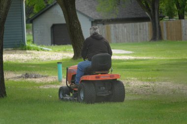 Yeni Lizbon, Wisconsin ABD - 23 Mayıs 2025: Çim biçme makinesiyle bahçelerinde çimleri biçen adamın arka planı.