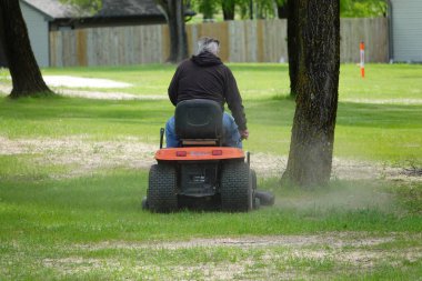 Yeni Lizbon, Wisconsin ABD - 23 Mayıs 2025: Çim biçme makinesiyle bahçelerinde çimleri biçen adamın arka planı.