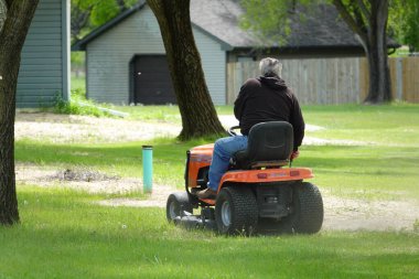 Yeni Lizbon, Wisconsin ABD - 23 Mayıs 2025: Çim biçme makinesiyle bahçelerinde çimleri biçen adamın arka planı.