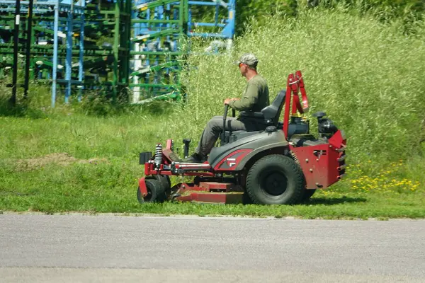 Fond du Lac, Wisconsin USA - July 22nd, 2025: Man cutting grass on a zero turn sit down lawnmower.