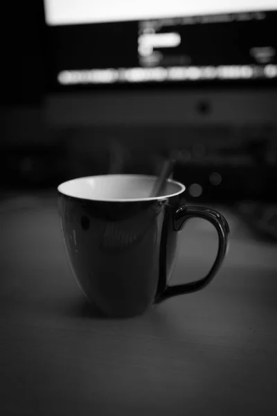 on the desk is a big black coffee cup