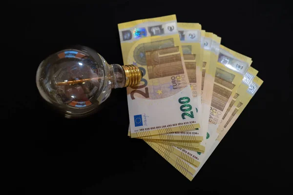 電球の横には200ユーロ紙幣の山があり — ストック写真