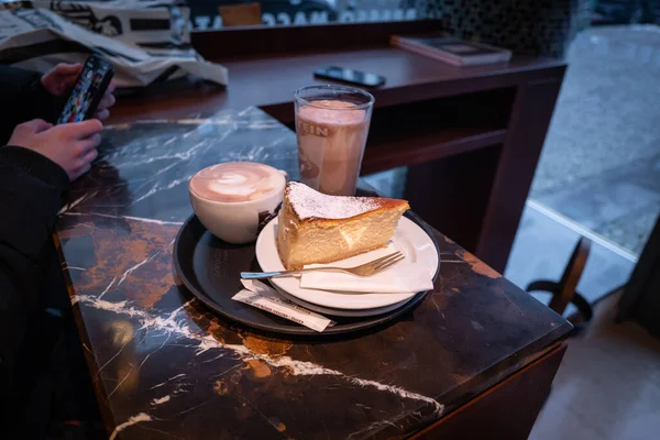 stock image on the table there is a piece of cheesecake, a glass of cocoa and a cup of cappuccino 