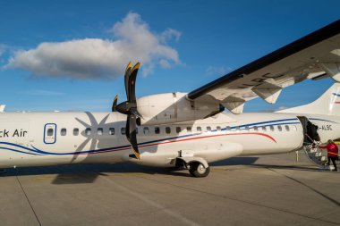 some Passengers go to the white propeller plane of Luebeck Air at Luebeck Airport