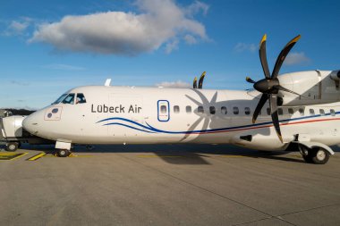 some Passengers go to the white propeller plane of Luebeck Air at Luebeck Airport