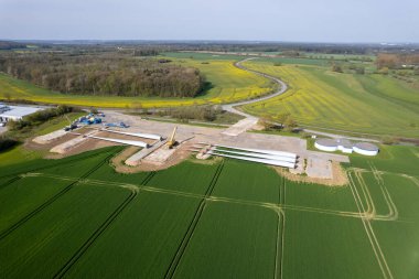 Yolun yanında bir rüzgar türbininin pervaneleri uzanır.