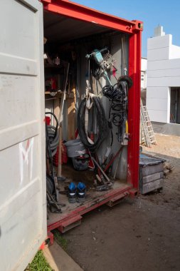İnşaat konteynırında çeşitli araç gereçler ve çalışma ekipmanları var.