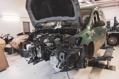 Önü ve kaputu olmayan bir araba garajda duruyor.