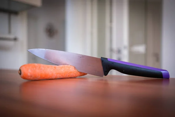 A knife cuts into a carrot