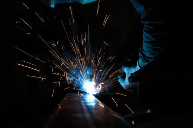 Kaynak maskesi takan biri kaynak makinesiyle metalle çalışır ve kaynak işlemi sırasında kıvılcımlar yaratır.
