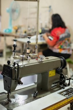 Professional overlock sewing machine. Equipment for edging, hemming or seaming clothes at tailors industry. garment factory shop. fashion designer workshop with craft clothing manufacturing