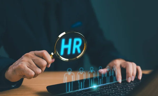 Human Resource Management HRM concept. Businessman use magnifying search human icon cluster for HR development recruitment. Business consulting technology for office meeting. Marketing communication