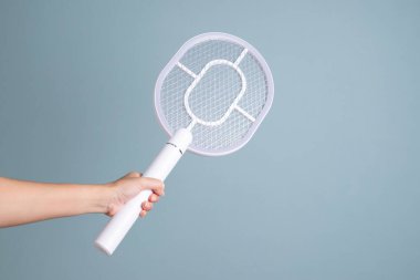 Kadın elinde sivrisinek elektronik raket katili, mavi arka planda izole edilmiş. Beyaz elektrikli sopa, böcek ya da küçük böcek öldürmek için tasarlanmış bir cihaz. Yarasa ya da tenis raketi elektrik gücü ev yaşam tarzı