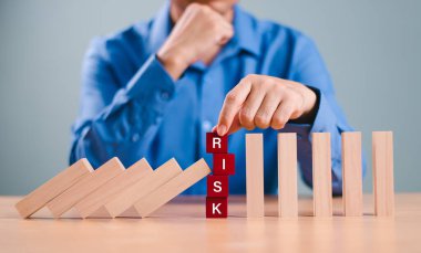  Risk değerlendirme krizi konsepti. Gayrimenkul işletmeleri için finansal analiz çözümü. Elle durdurma ekonomik risk. Tahta blokta risk kelimesi, domino krizi etkisini azaltır. Sigorta güvenliği. 