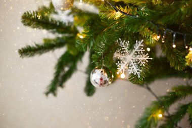 Arka planda süslenmiş Noel ağacı. Toplar ve çelenklerle süslenmiş güzel yeşil Noel ağacı. Yakın plan fotoğraf.