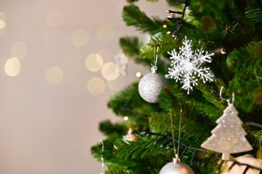 Arka planda süslenmiş Noel ağacı. Toplar ve çelenklerle süslenmiş güzel yeşil Noel ağacı. Yakın plan fotoğraf.