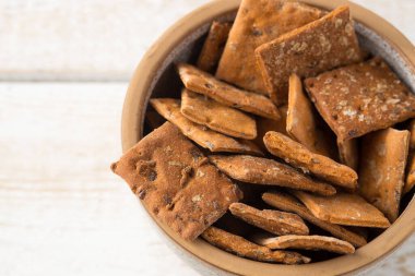 Hafif ahşap arka planda domates ve fesleğen tadında kuru krakerler. yakın plan.