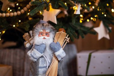 Noel Baba oyuncağı Noel ağacının altında, arka planda bulanık ışıklar var. Mutlu yıllar kavramı. Tatil kartı, poster.