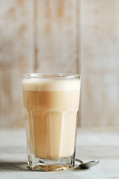 Raff coffee in a glass transparent glass on a light wood background. coffee with milk.