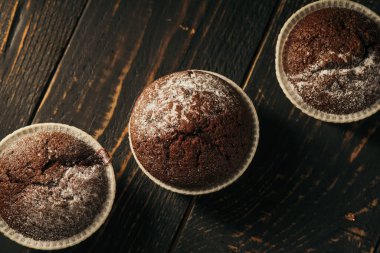 Siyah arka planda pudra şekerli çikolatalı kekler. Hayat yakın mesafede. Karamsar. Yemek fotoğrafı.