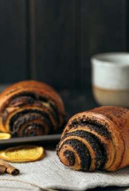 Haşhaş tohumlu çörekler ve koyu ahşap arka planda bir fincan kahve..