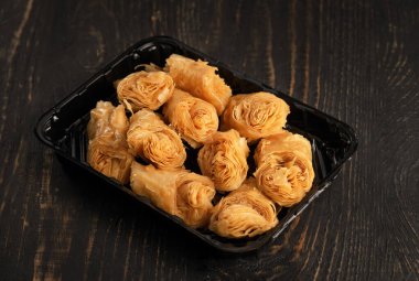 Koyu ahşap arka planda bir mağaza veya teslimat servisi için mini el sanatları paketinde ceviz bulunan Türk Ramazan Tatlısı Baklava