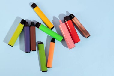 Mavi arka planda tek kullanımlık renkli elektronik sigaralar. Modern sigara konsepti. Üst görünüm