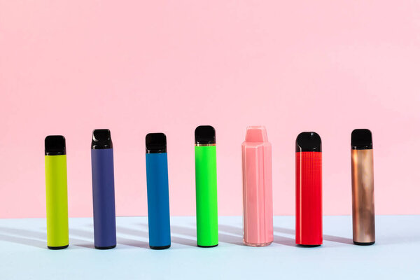 Set of colorful disposable electronic cigarettes on a pink background. The concept of modern smoking