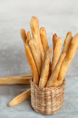 Grissini with herbs on a gray concrete background.
